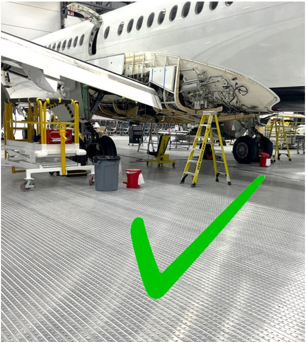 Aircraft under maintenance on spill-resistant flooring with green checkmark.