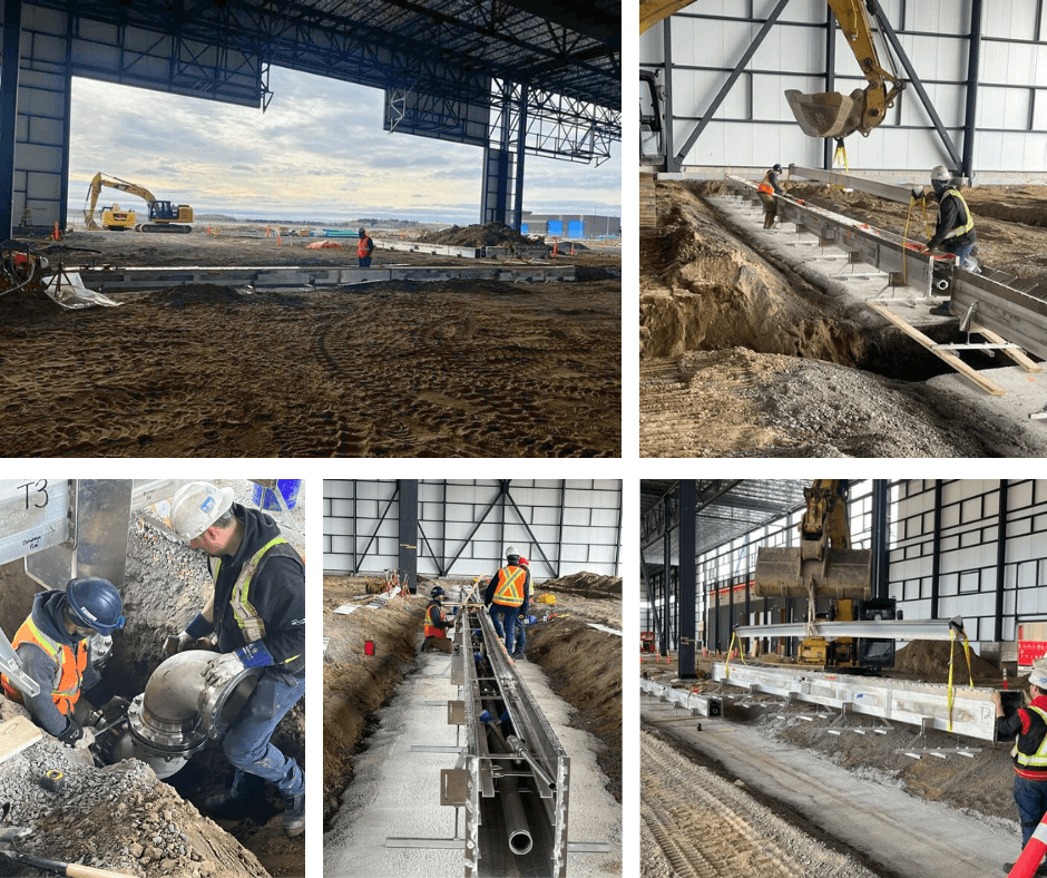 Construction workers install industrial drainage systems inside a large warehouse.
