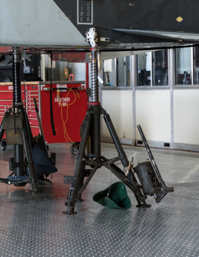 Aircraft jacked up in a maintenance hangar with tools and red tool chest nearby.