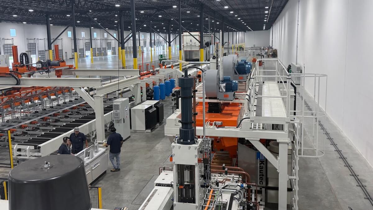 Manufacturing plant with machinery in operation, workers overseeing production line in a spacious industrial setting.