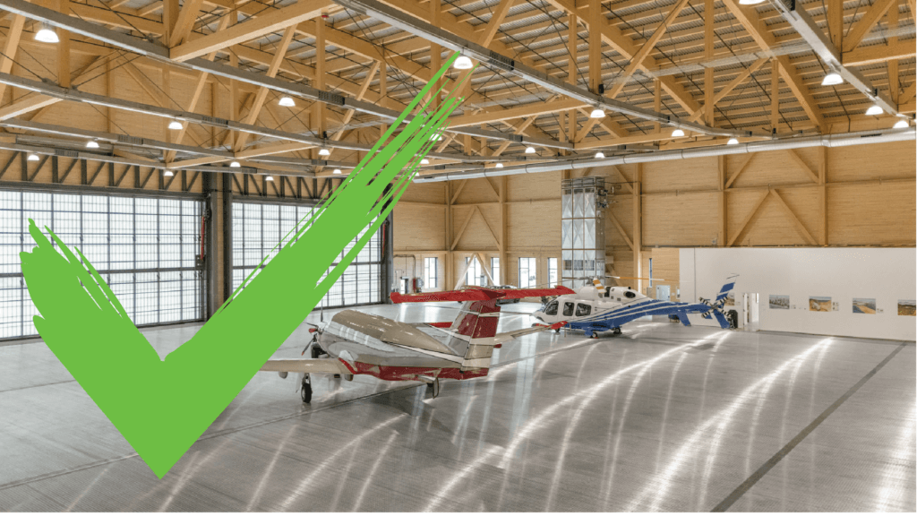 Aircraft parked in a spacious hangar with a green checkmark overlay on the left side.