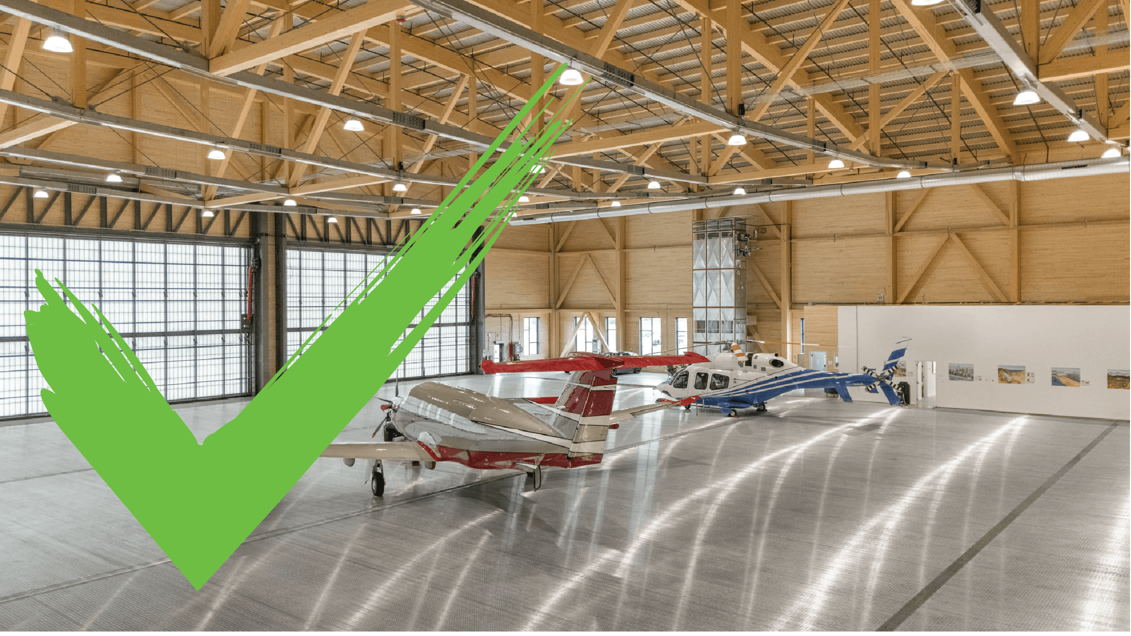 Aircraft parked in a spacious hangar with a green checkmark overlay on the left side.