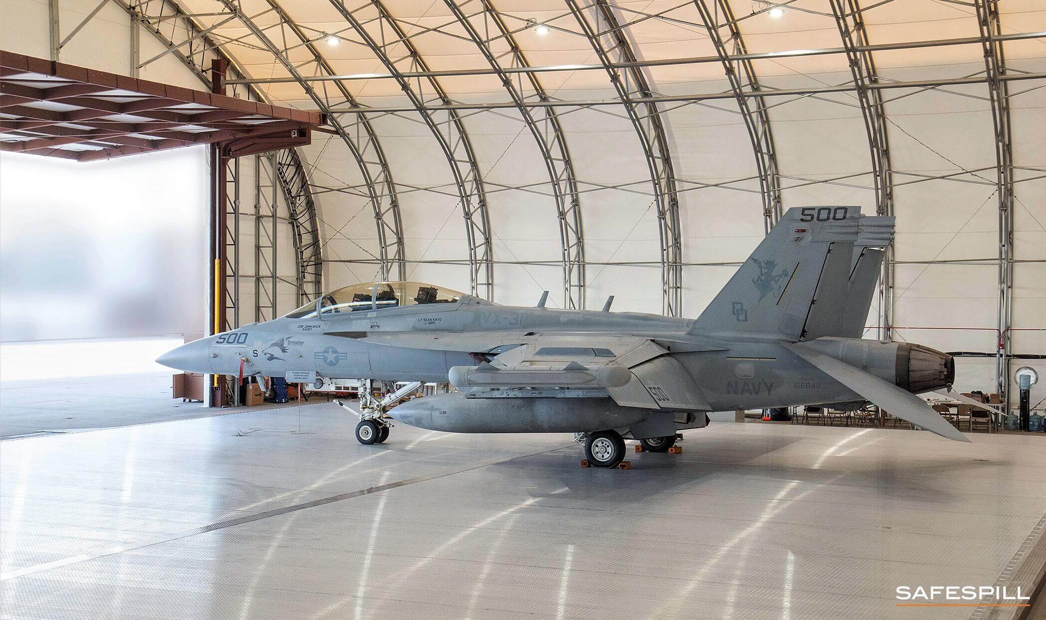 A fighter jet parked inside a spacious hangar with curved ceiling supports.