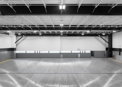 Spacious industrial warehouse interior with high ceilings and bright overhead lighting.