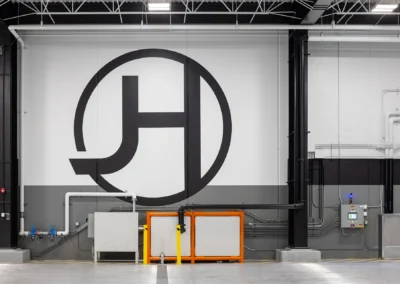 Large industrial symbol on a white warehouse wall with pipes and equipment.