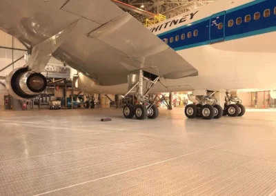 Jet in hangar with visible landing gear and engine, surrounded by maintenance equipment.