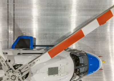 Helicopter top view with red and white rotor blades on a metallic surface background.
