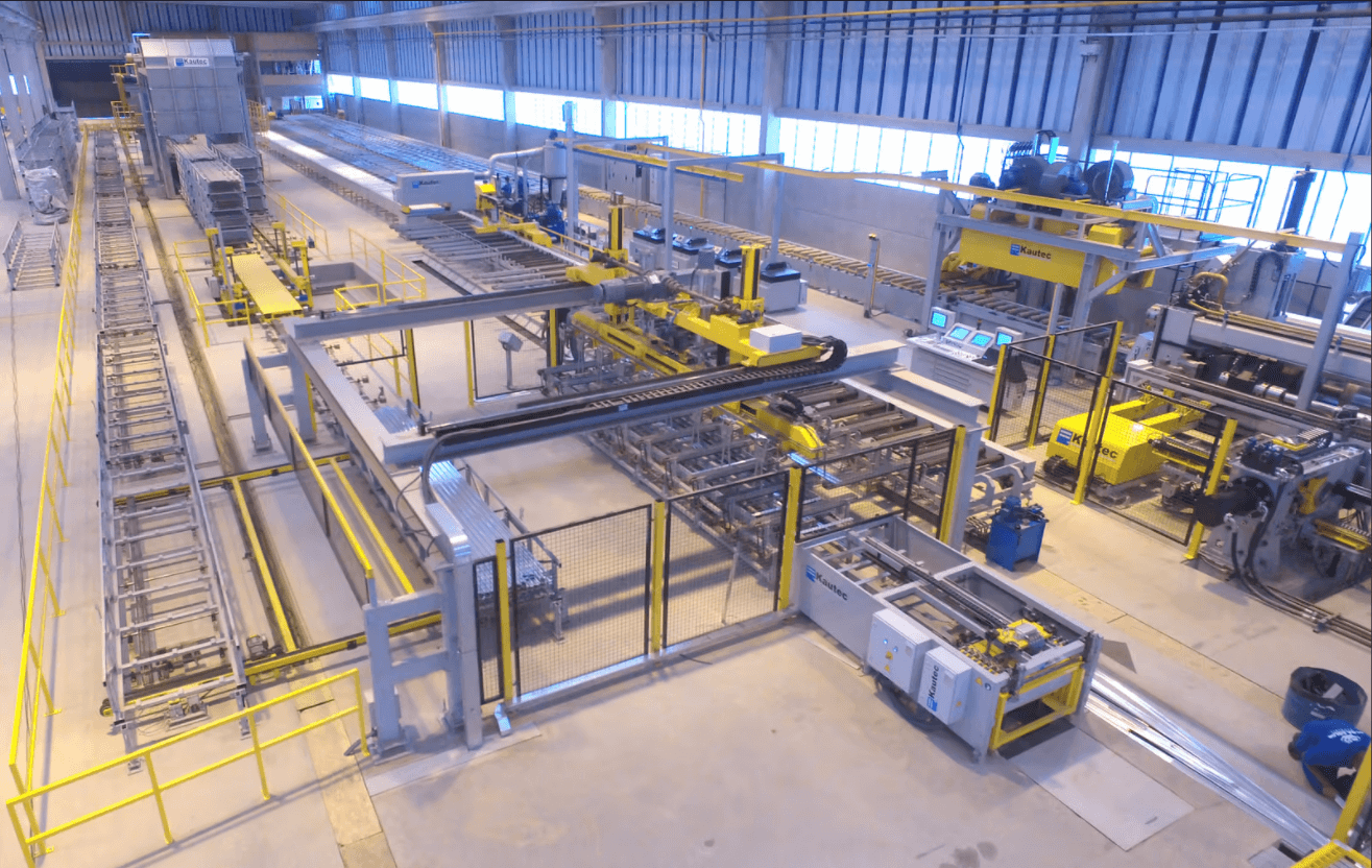 Industrial automated assembly line with machinery in operation, featuring yellow safety rails and control panels.