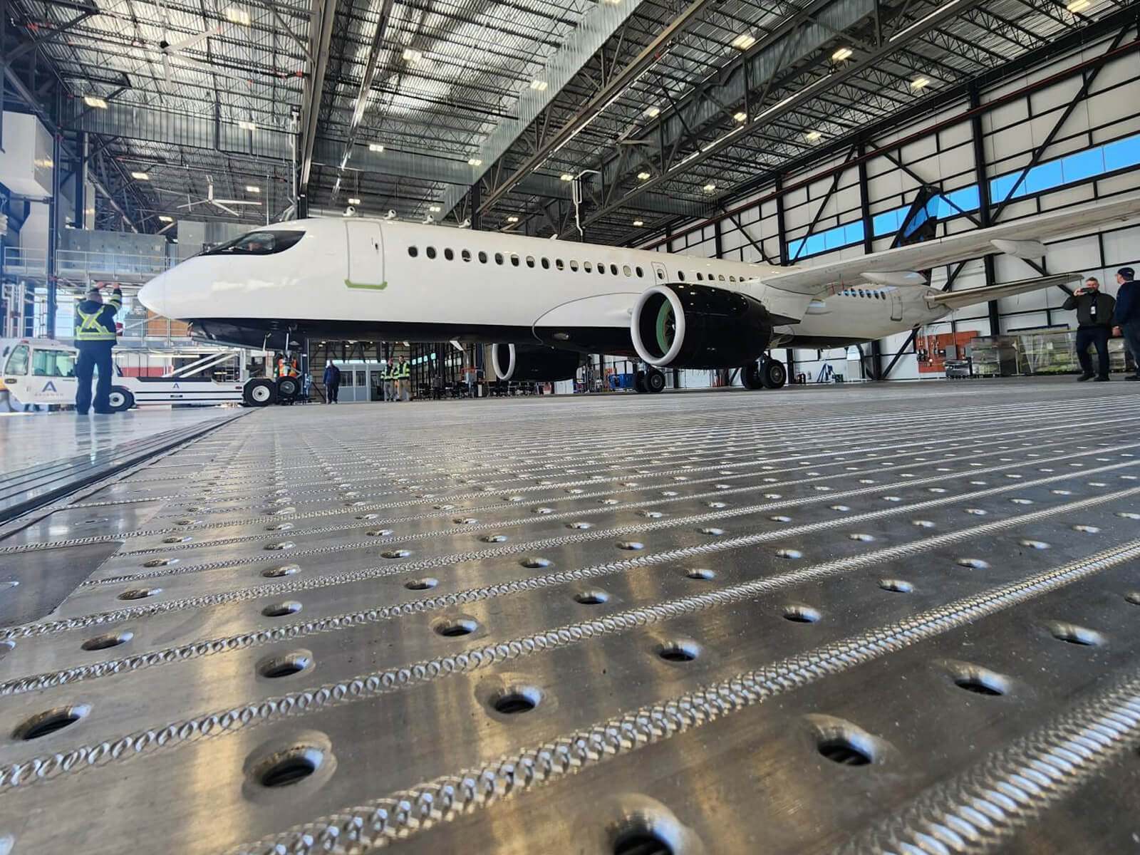 Airplane inside a spacious hangar with technicians preparing for maintenance.