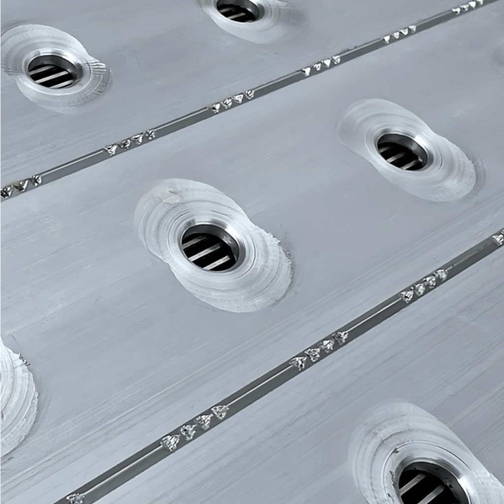 Smooth metal surface with circular grooves and drainage holes.