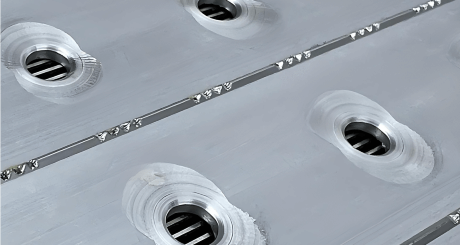 Grooved metal surface with embedded drains, designed for efficient liquid spill management.
