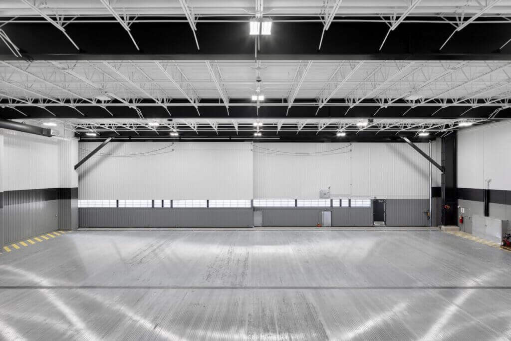 Spacious, empty warehouse interior with a high ceiling and bright lighting.