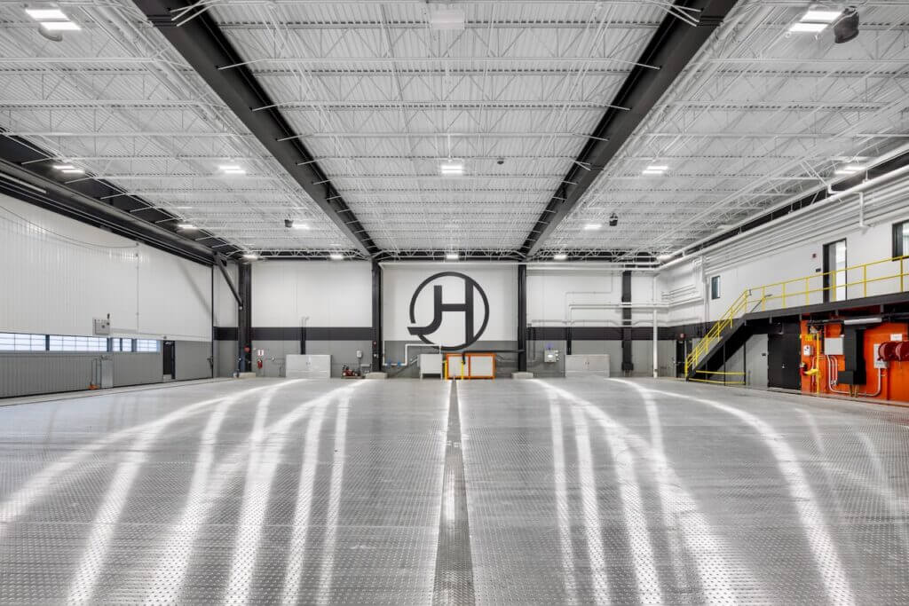 Spacious industrial warehouse interior with metallic flooring, high ceiling, and bright lighting.