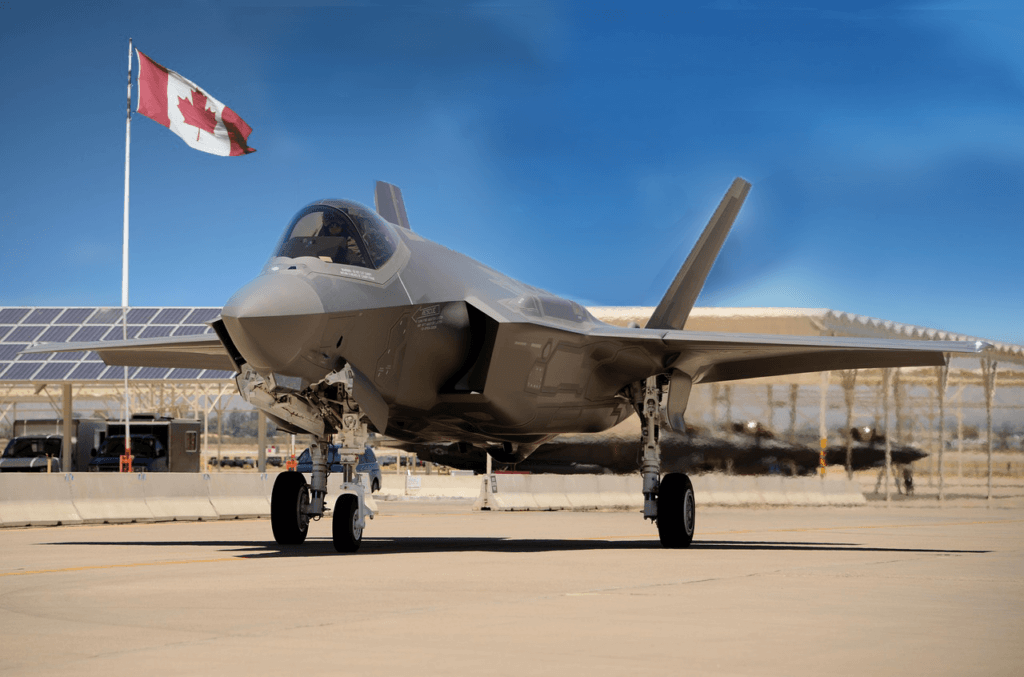 Jet fighter parked on runway, Canadian flag waving under a clear blue sky.