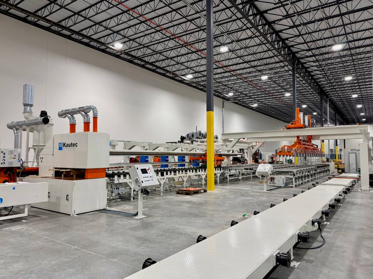 Industrial manufacturing line with machinery under a high ceiling, ready for production in a large facility.