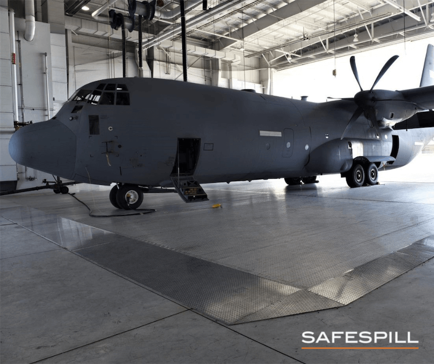 Cargo plane parked in a spacious hangar with open side door and visible landing gear.