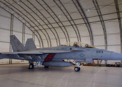Fighter jet parked inside a spacious aircraft hangar.