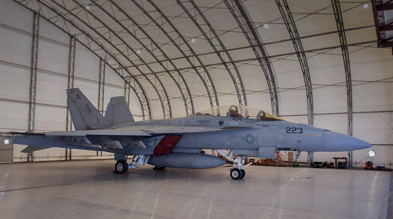 Fighter jet parked inside a spacious aircraft hangar.