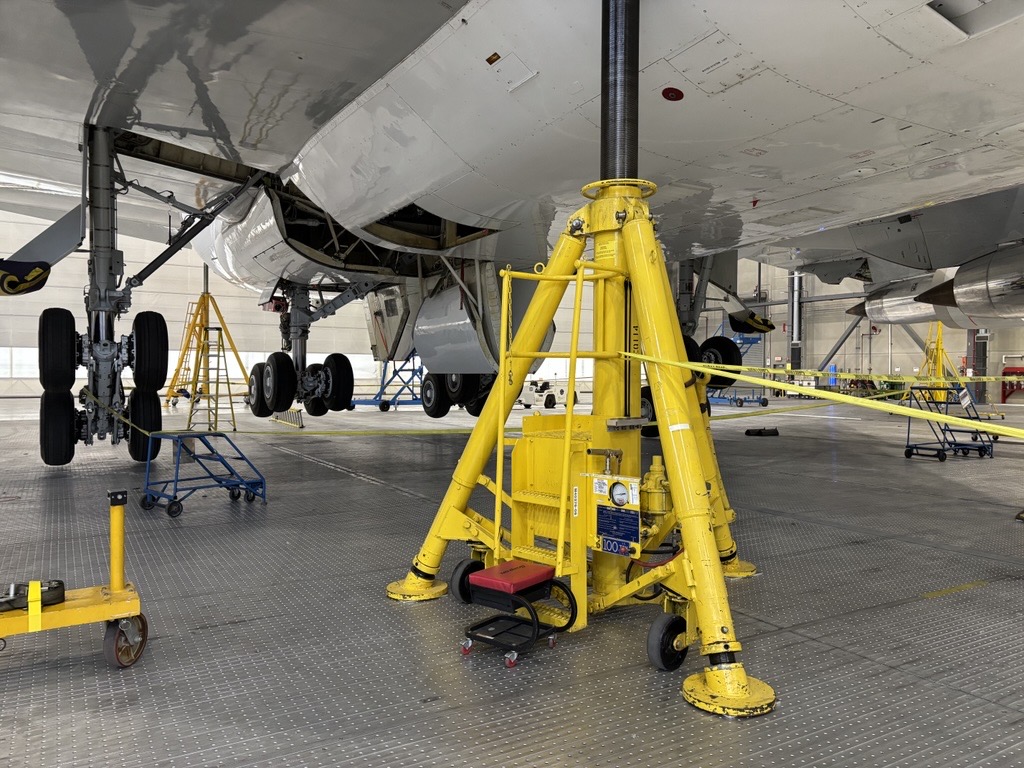 747 Jacked Man operating a floor scrubber in an industrial warehouse setting.